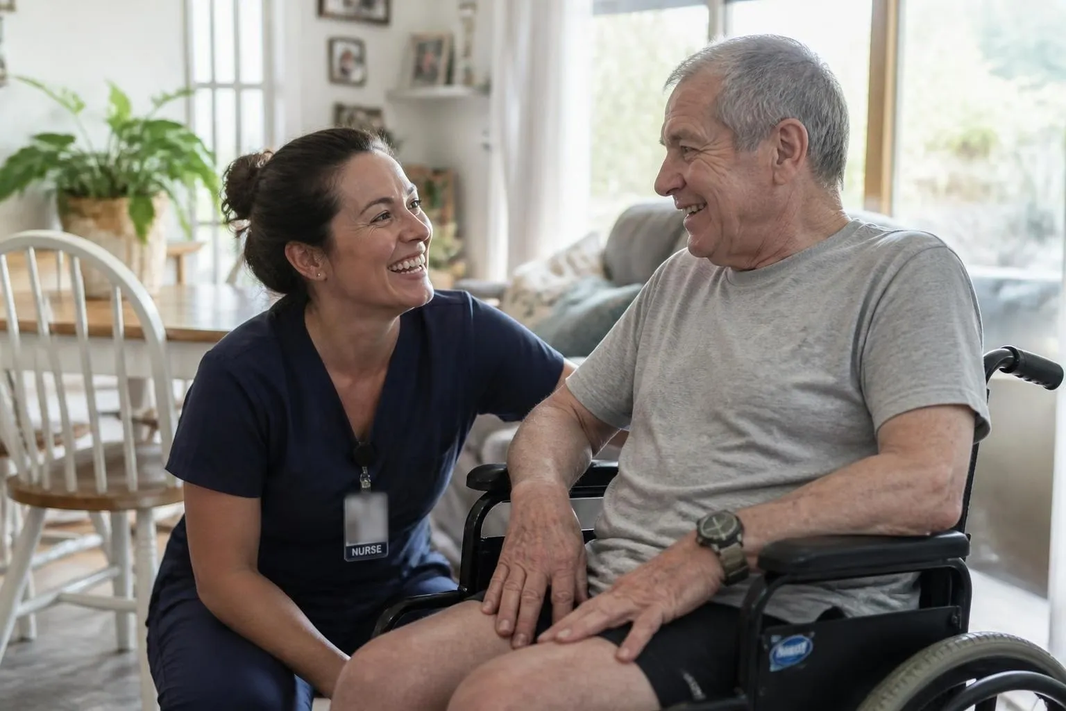 Nurse sharing a laugh with an older man in a wheelchair at home